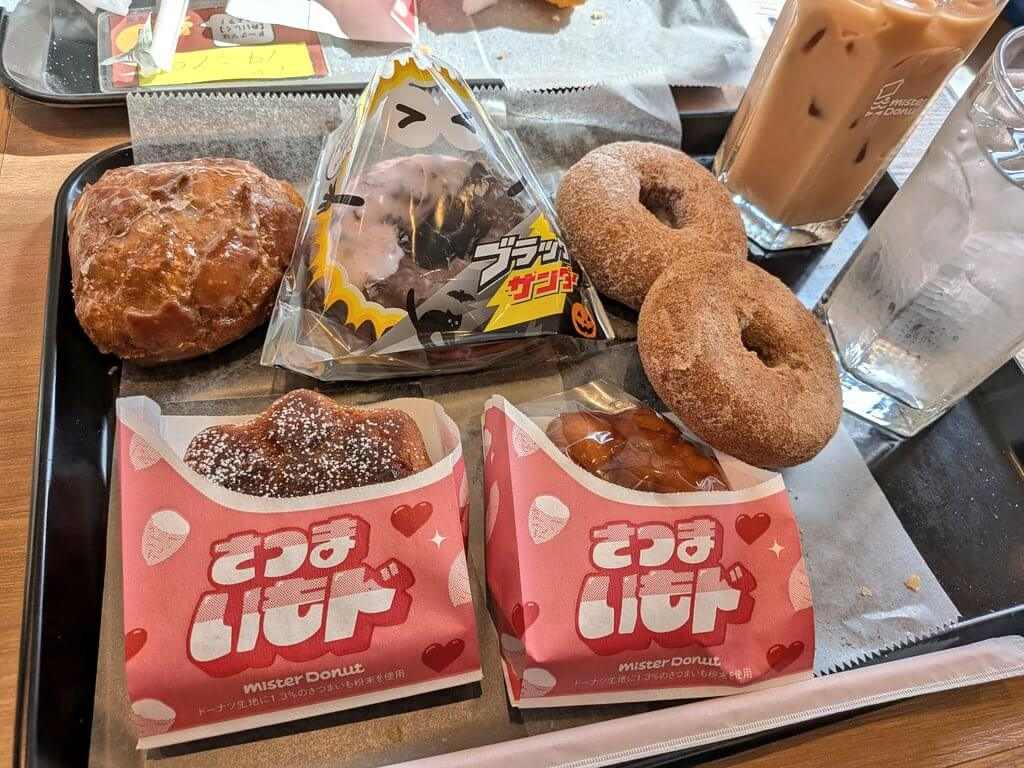 トレーに沢山の期間限定ミスド食べ放題のドーナツとアイスカフェオレが乗っている画像