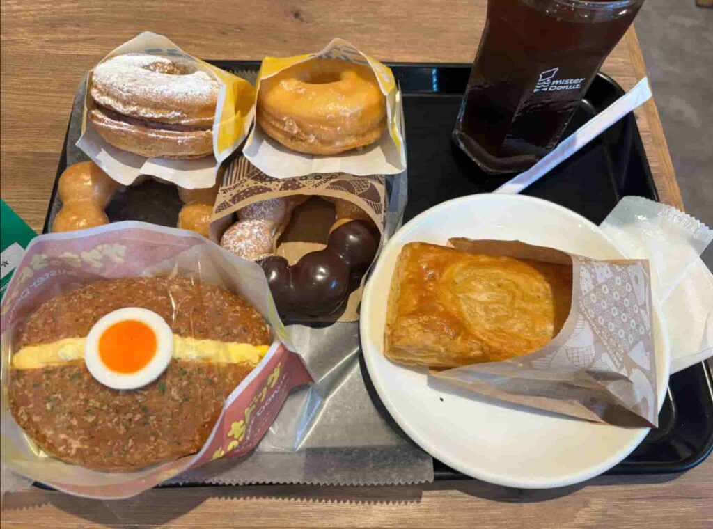 ミスドの食べ放題で、たくさんのドーナツやパイがトレーに載っている画像