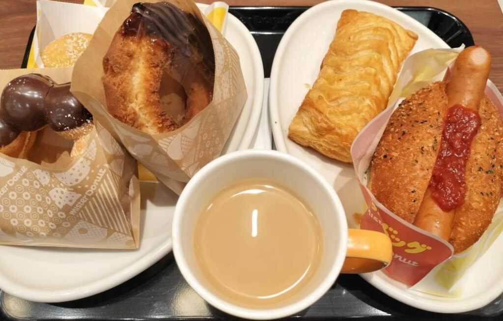 ミスドのカフェオレとドーナツやパイがお皿に沢山のった画像