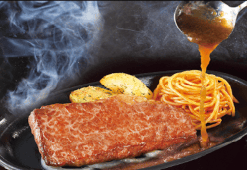 鉄板焼きステーキにソースをかけている画像